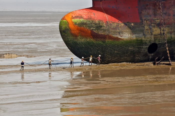 Workers carry a rope line to fasten a decommissioned ship at the Alang shipyard in the western Indian state of Gujarat, March 27, 2015. To match Insight SHIPPING-INVESTMENT/BEACHING REUTERS/Amit Dave/File Photo