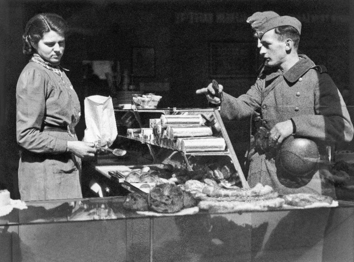 Illustrasjonsfoto: Oslo 22. april 1940. Tyske soldater gjør innkjøp i bakerforretning, og blir ekspedert av ung kvinne. FOTO: Krigsarkivet / NTB scanpix